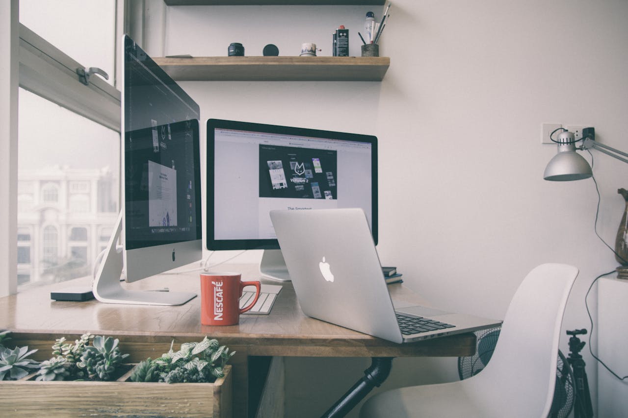 Sleek home office setup with dual monitors, a laptop, and minimalist decor.